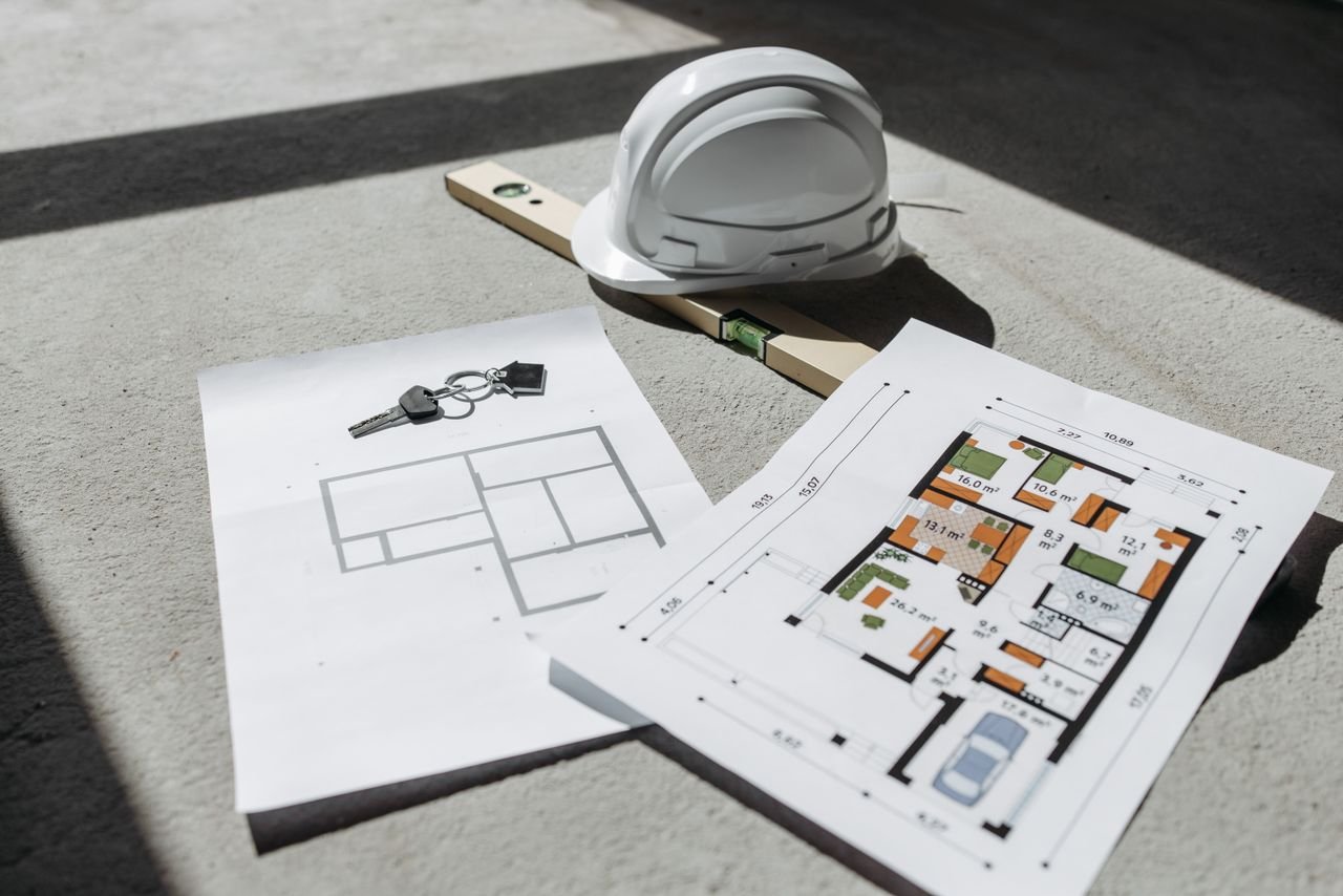 Home Architectural floor plans with helmet and keys on sunlit floor, perfect for real estate or construction themes.