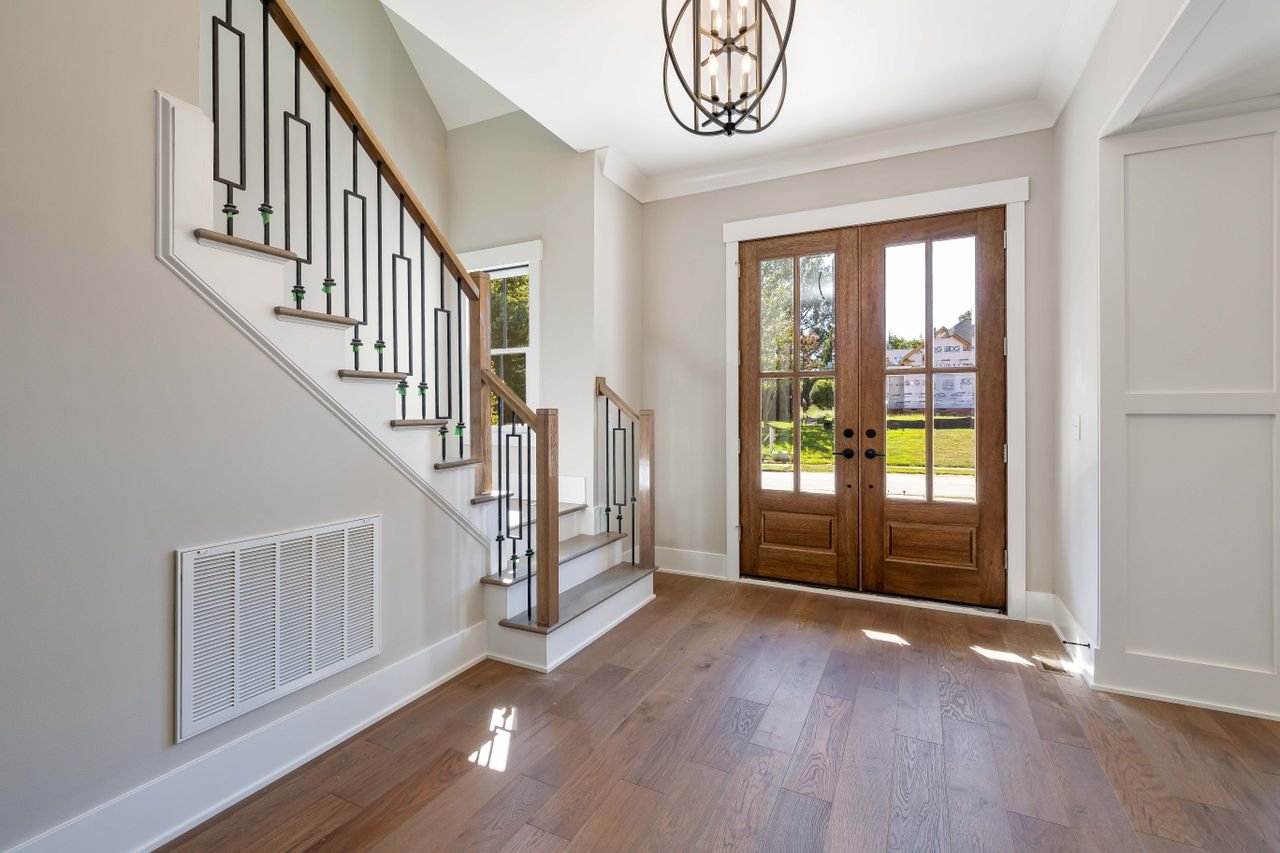 Services Elegant and spacious house entrance featuring wooden doors and staircase.
